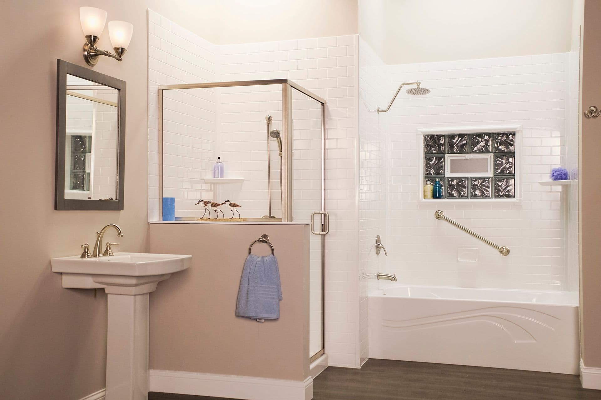 A bathroom with a stand-alone glass shower stall and separate bathtub shower combination with a diagonal grab bar.