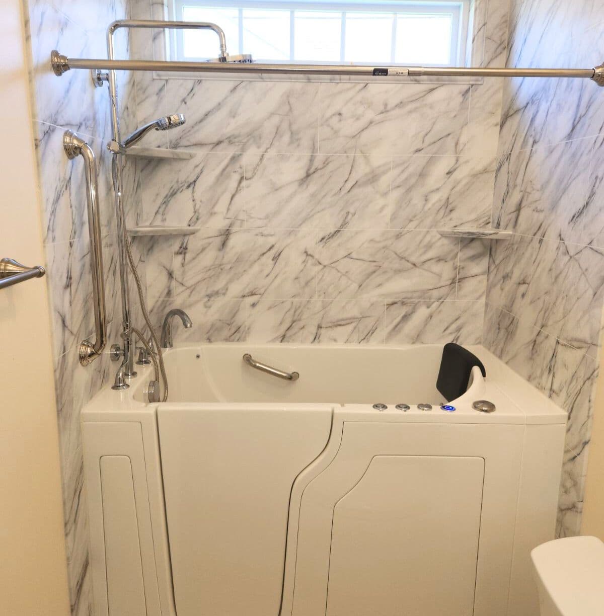 A walk-in bathtub and shower combination with gray and white marbled walls.